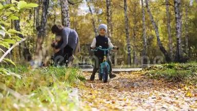 秋天公园里落叶时骑自行车的快乐小男孩。 快乐的童年。 慢动作。 3840x2160